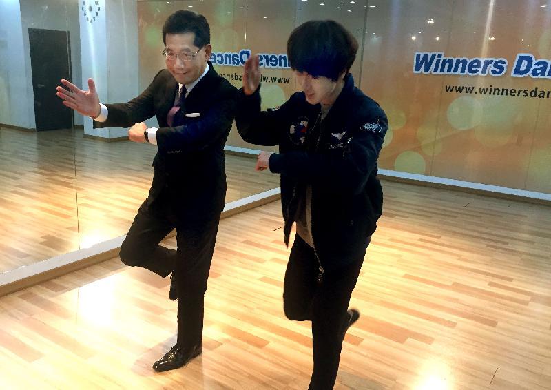 Mr So visited a K-pop dance school in the afternoon. He toured the dance studios and was briefed on the variety of training programmes and workshops for young people. Picture shows a young dancer showing Mr So (left) a variety of K-pop dance steps.