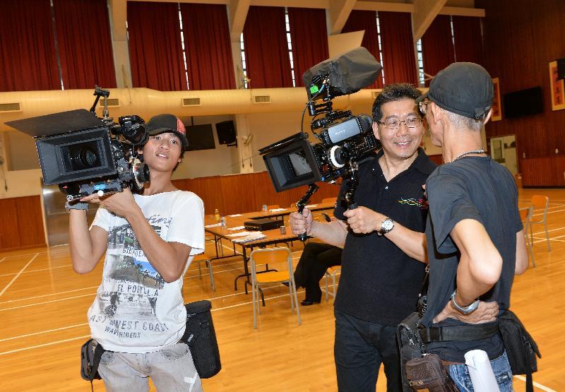 Mr So (second right) listens to the production crew's introduction of the filming equipment.